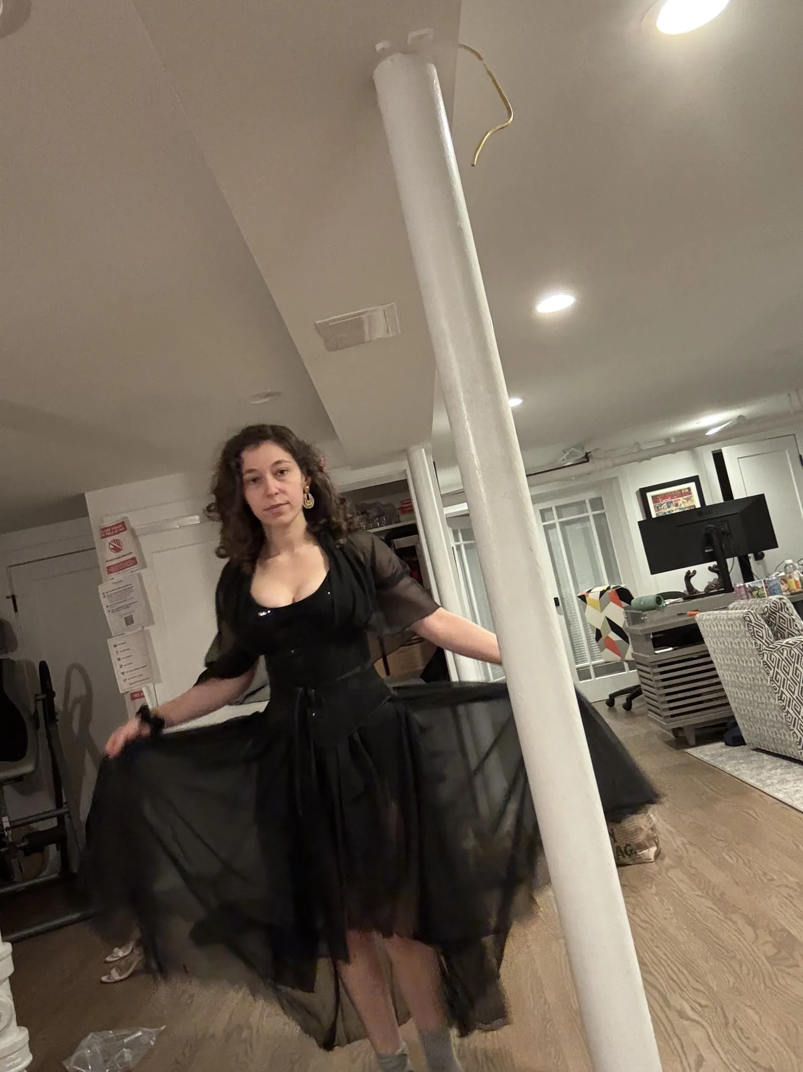 A person in a black dress holds out the sheer skirt to show its wide shape.