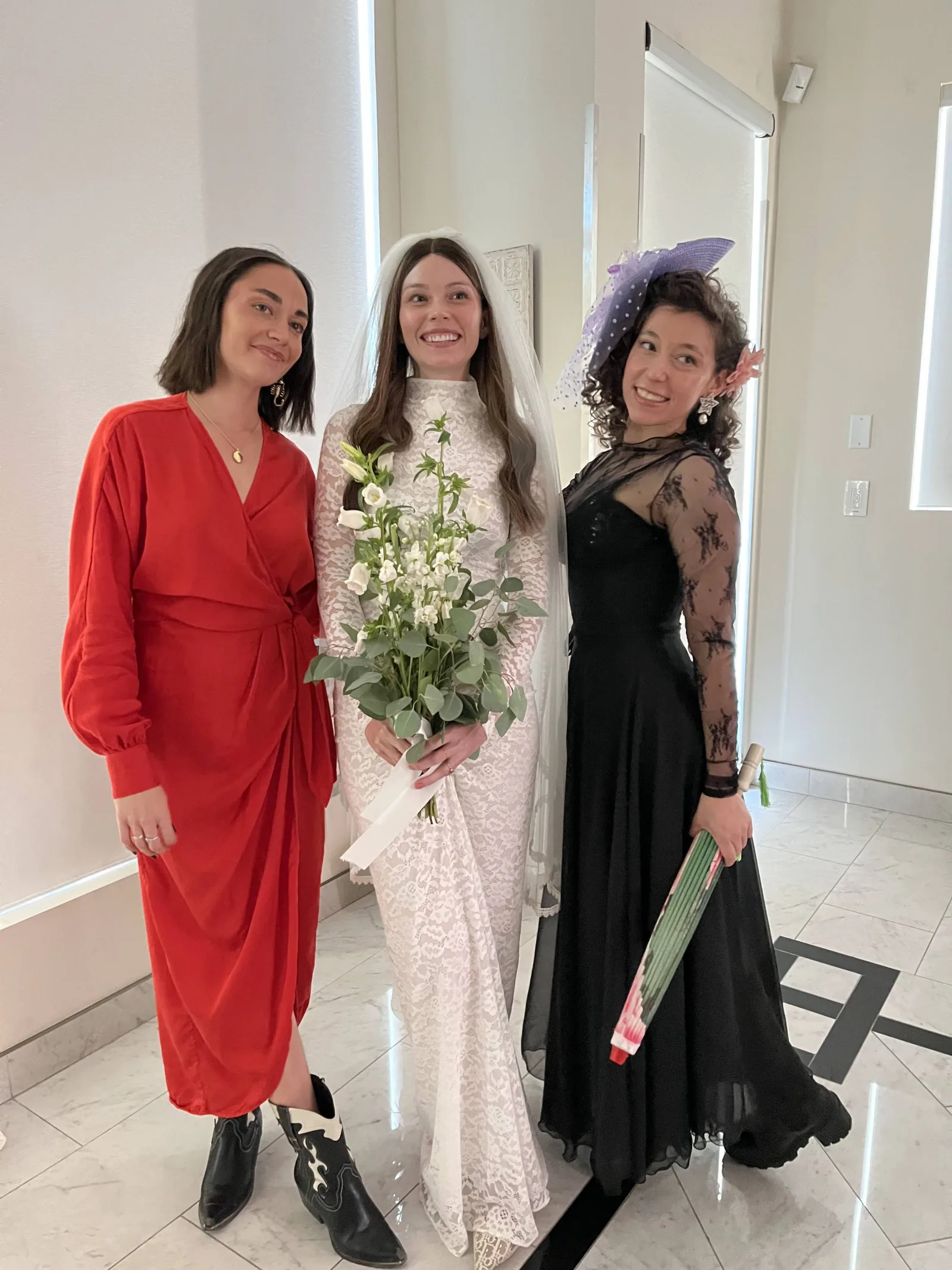 Dashiell stands with the bride and another guest in a black lace top and long skirt.