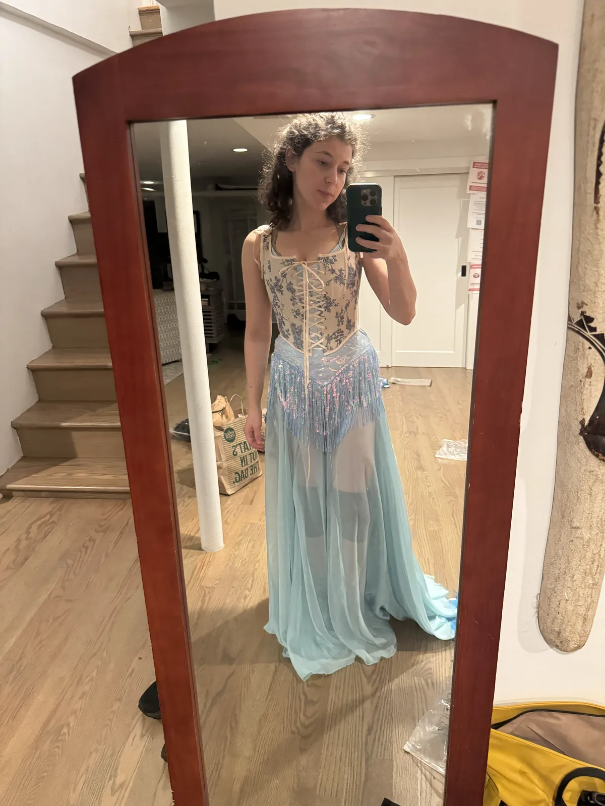 Full-length mirror selfie wearing a pale blue corset with a sheer light blue skirt.