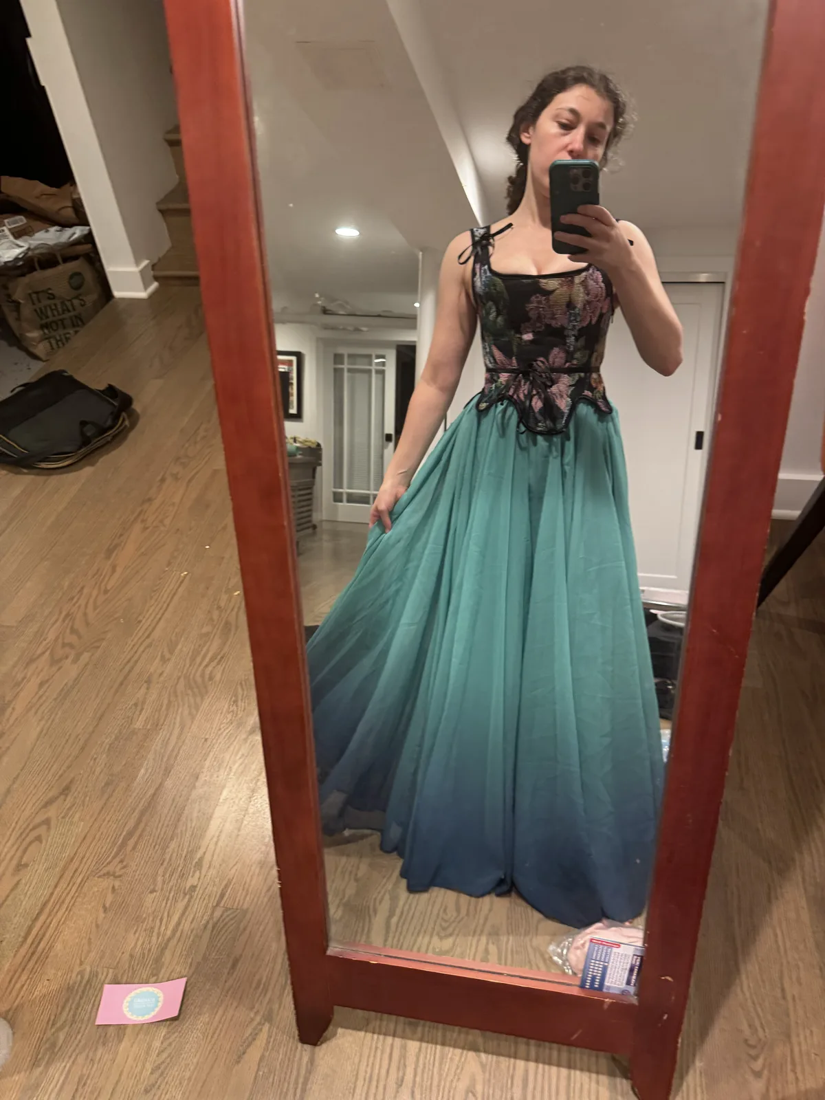 Mirror selfie wearing a floral black corset with a full turquoise skirt.