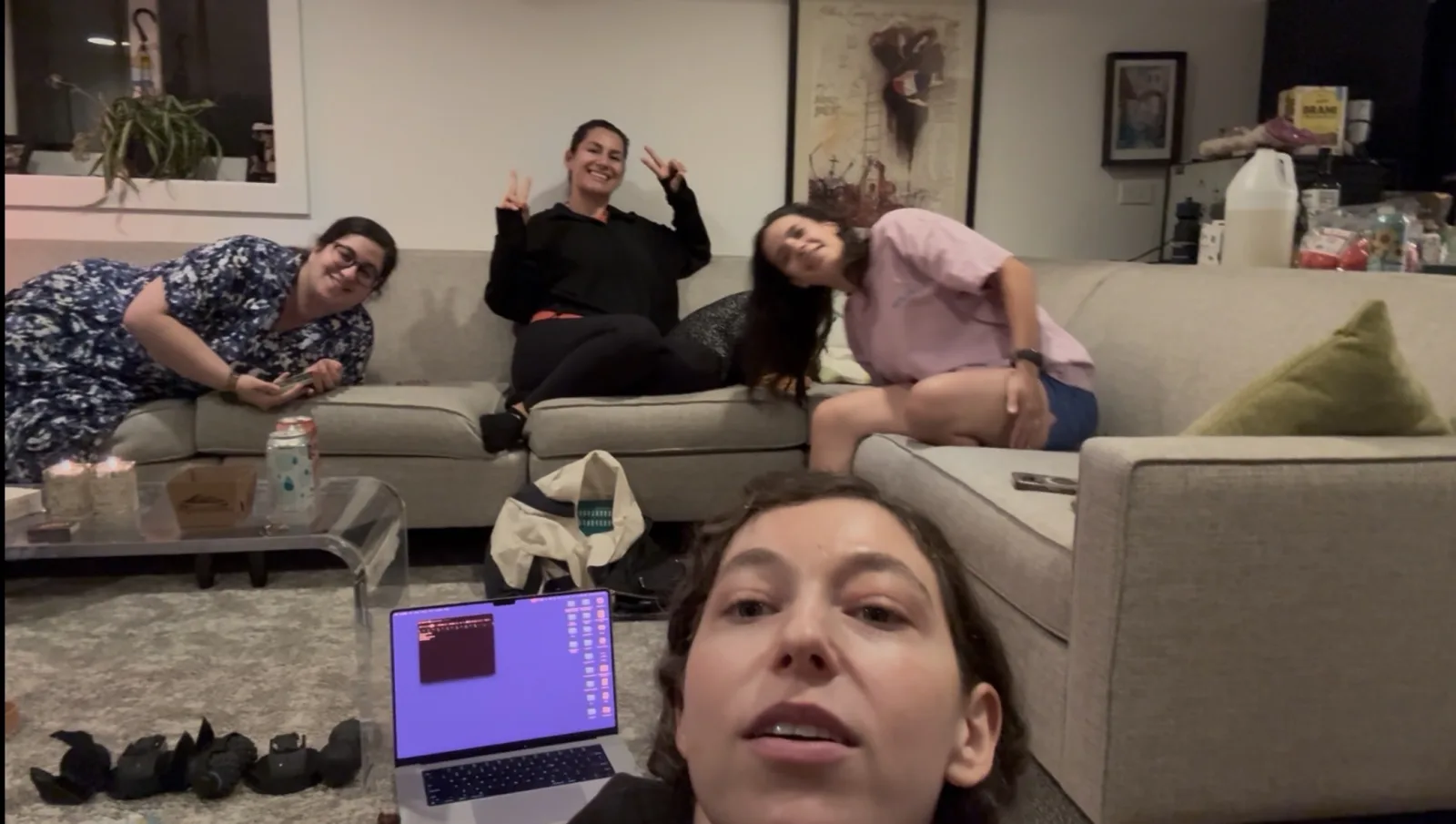 Four women smiling together around a laptop during vision-boarding night.